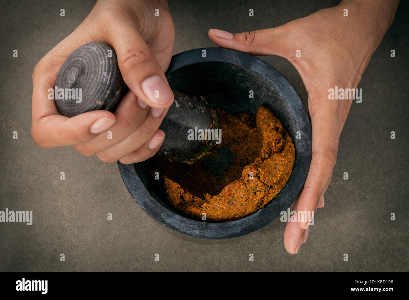 The Women hold pestle with mortar and and spice red curry paste