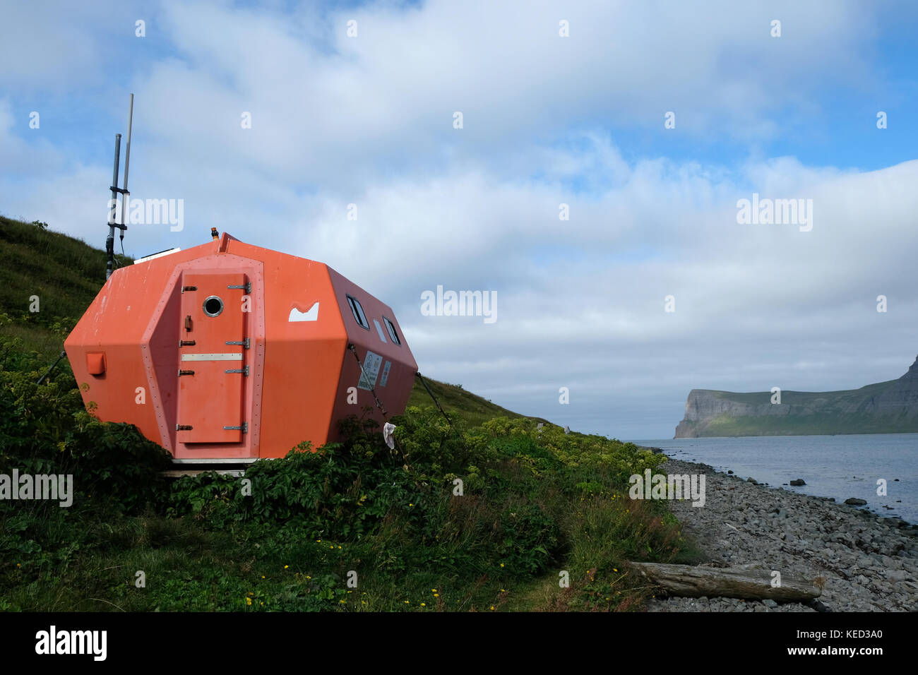 Bright orange emergency rescue shelter hut in remote standing in Hornvik Bay, Hornstrandir nature reserve, Westfjords, North Iceland Stock Photo