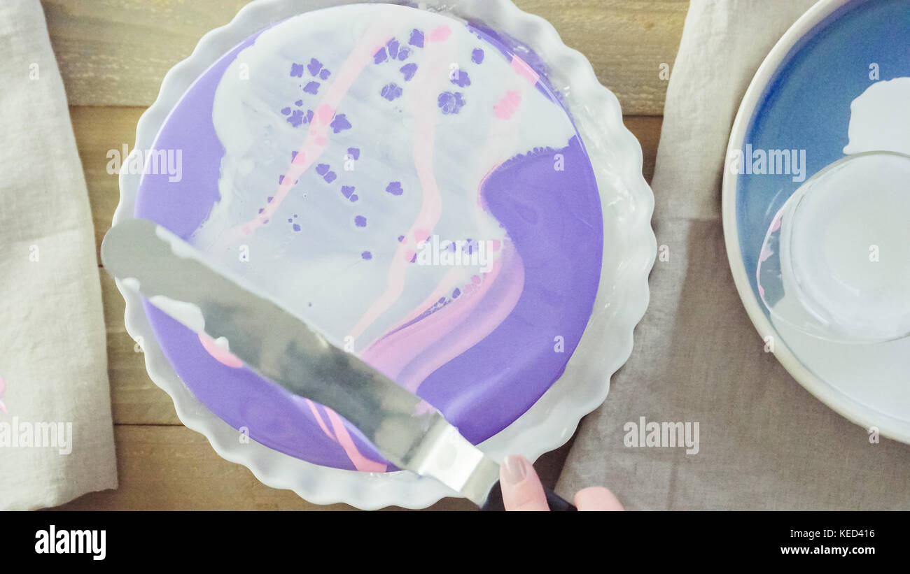 Step by step. Pastre shef making mousse cake with purple mirror glaze and decorated with chocolate pink flowers. Stock Photo