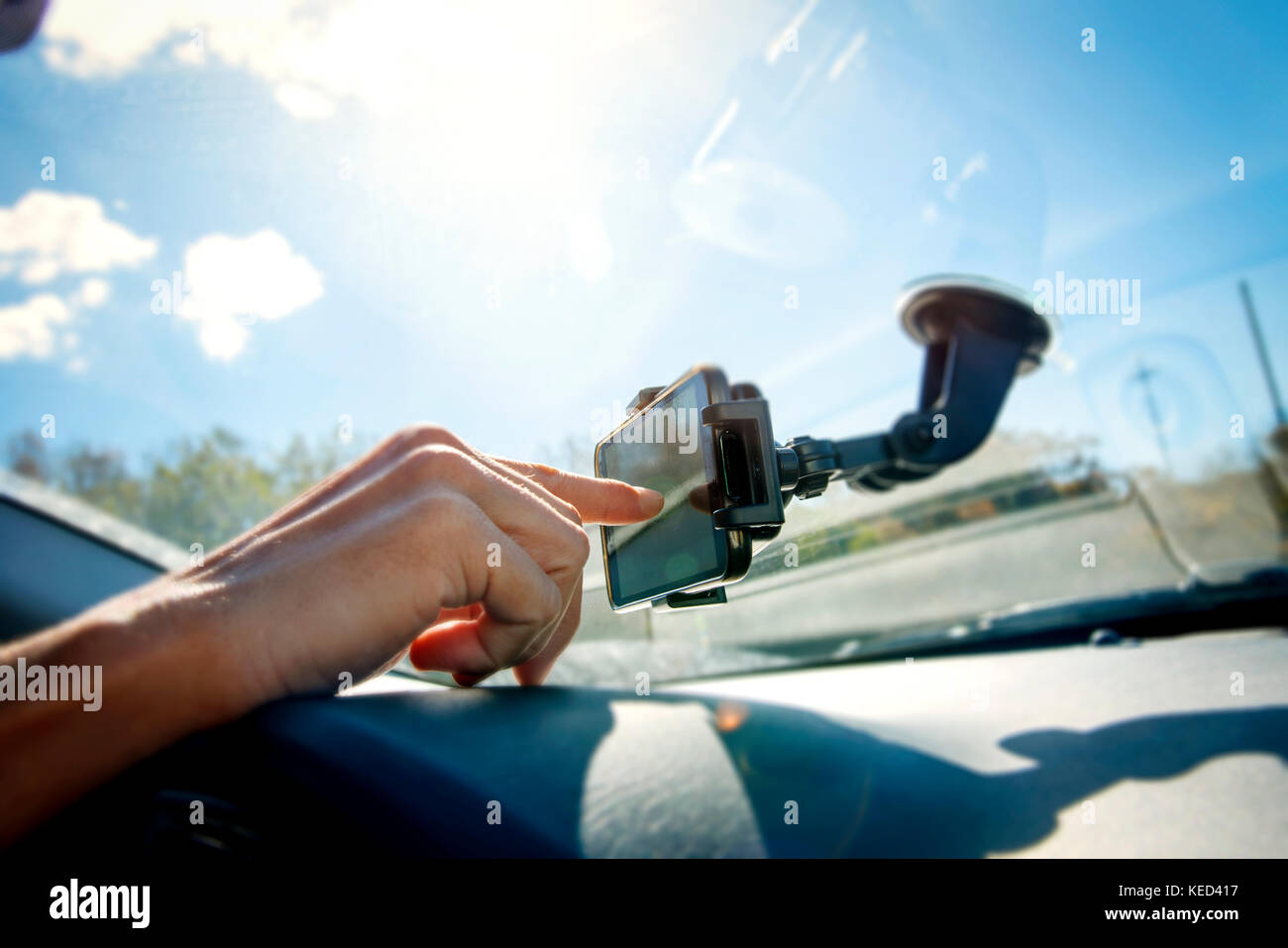closeup of a young caucasian man using a smartphone as a GPS mounted in a holder stuck in the windscreen of a car Stock Photo