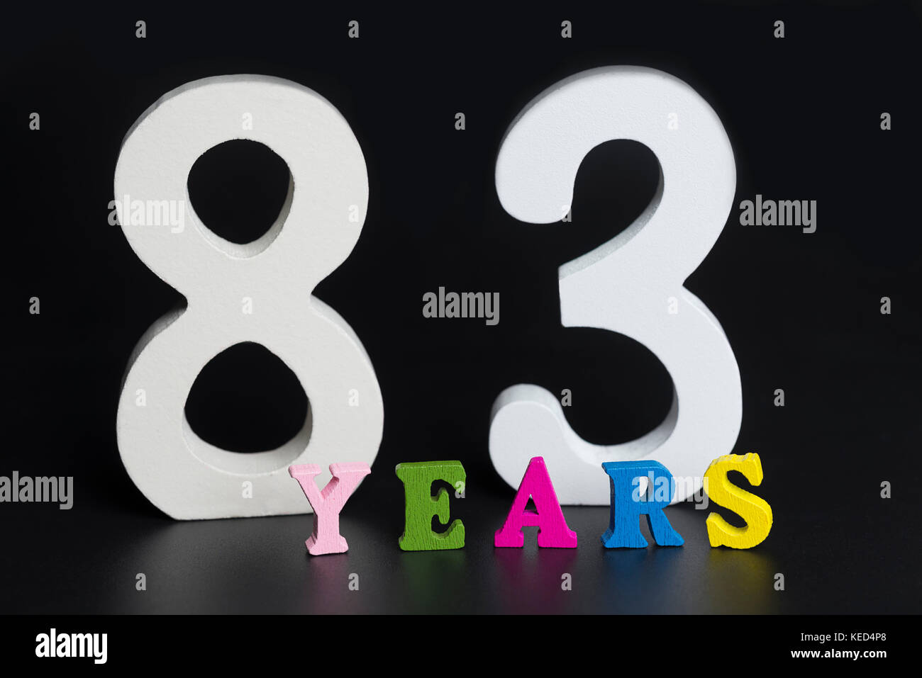 Letters and numbers eighty-three years on black isolated background. Stock Photo
