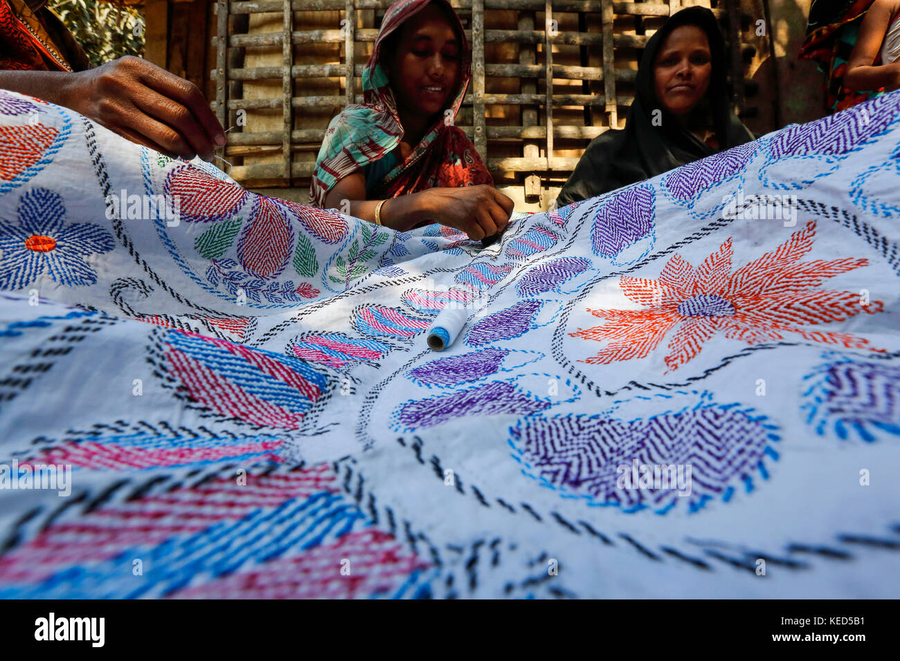 Rural women make Nakshi Kantha, a type of embroidered quilt at a village in Jessore. Bangladesh. Stock Photo