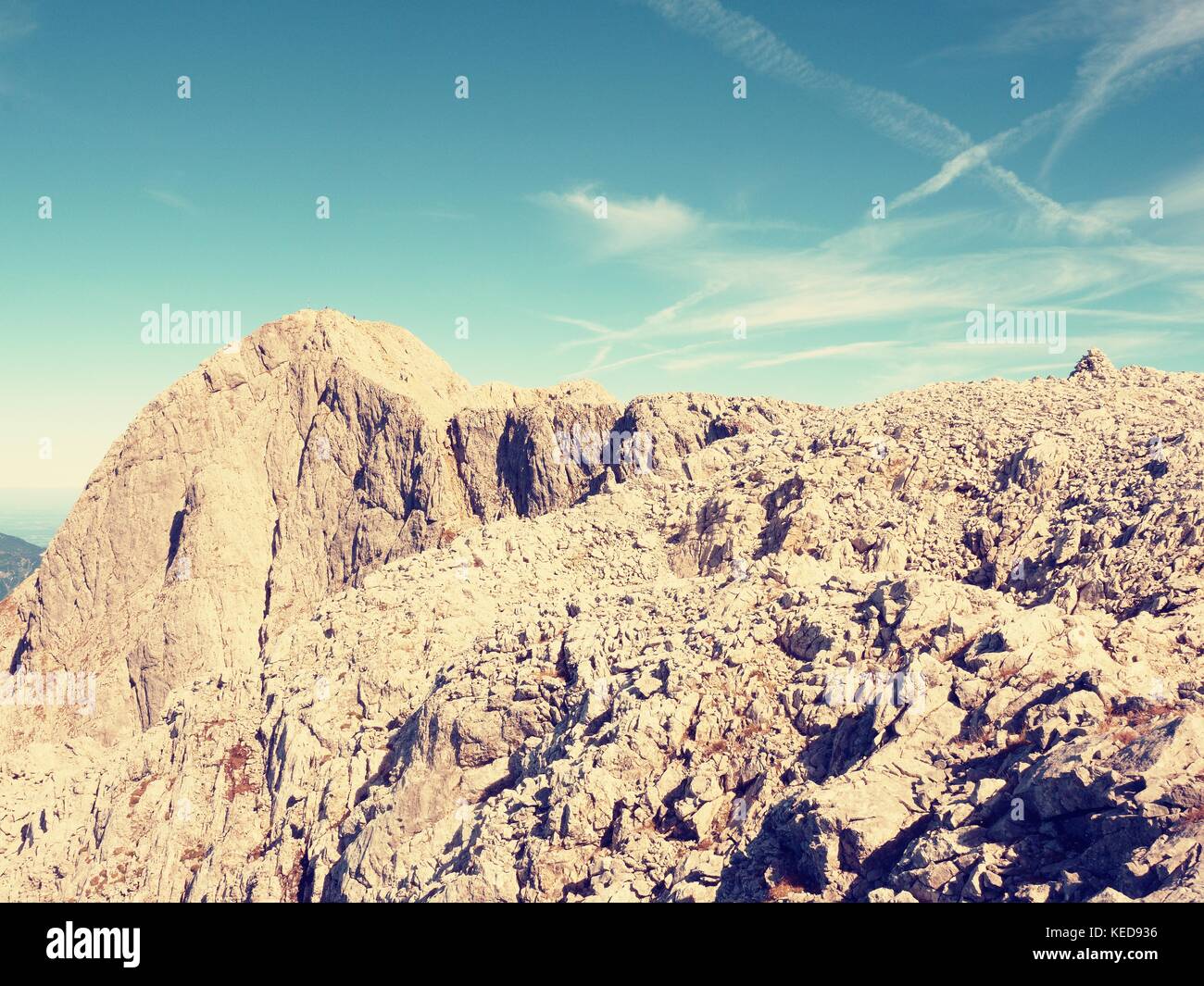 View over Alpine cliff and valley. Sun at horizon, blue sky with few ...