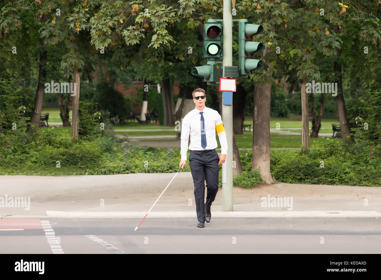 Young Blind Man Holding Stick Crossing Road Stock Photo