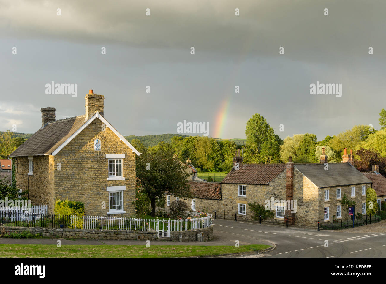 The crossroads in the pretty North Yorkshire village of Coxwold, with a rainbow over the distant hills Stock Photo