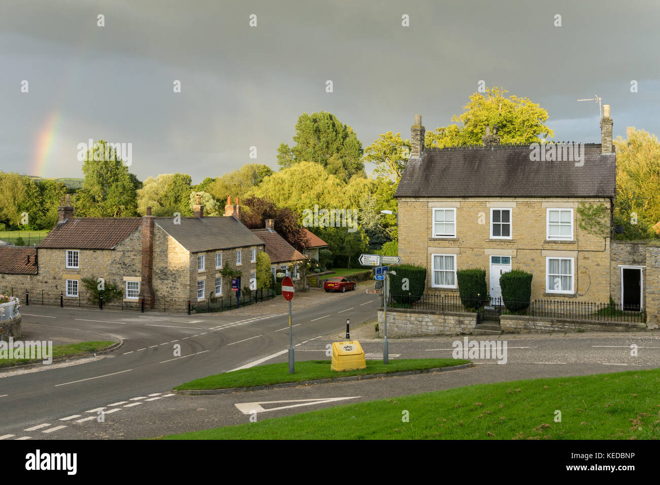 The crossroads in the pretty North Yorkshire village of Coxwold, with a rainbow over the distant hills Stock Photo