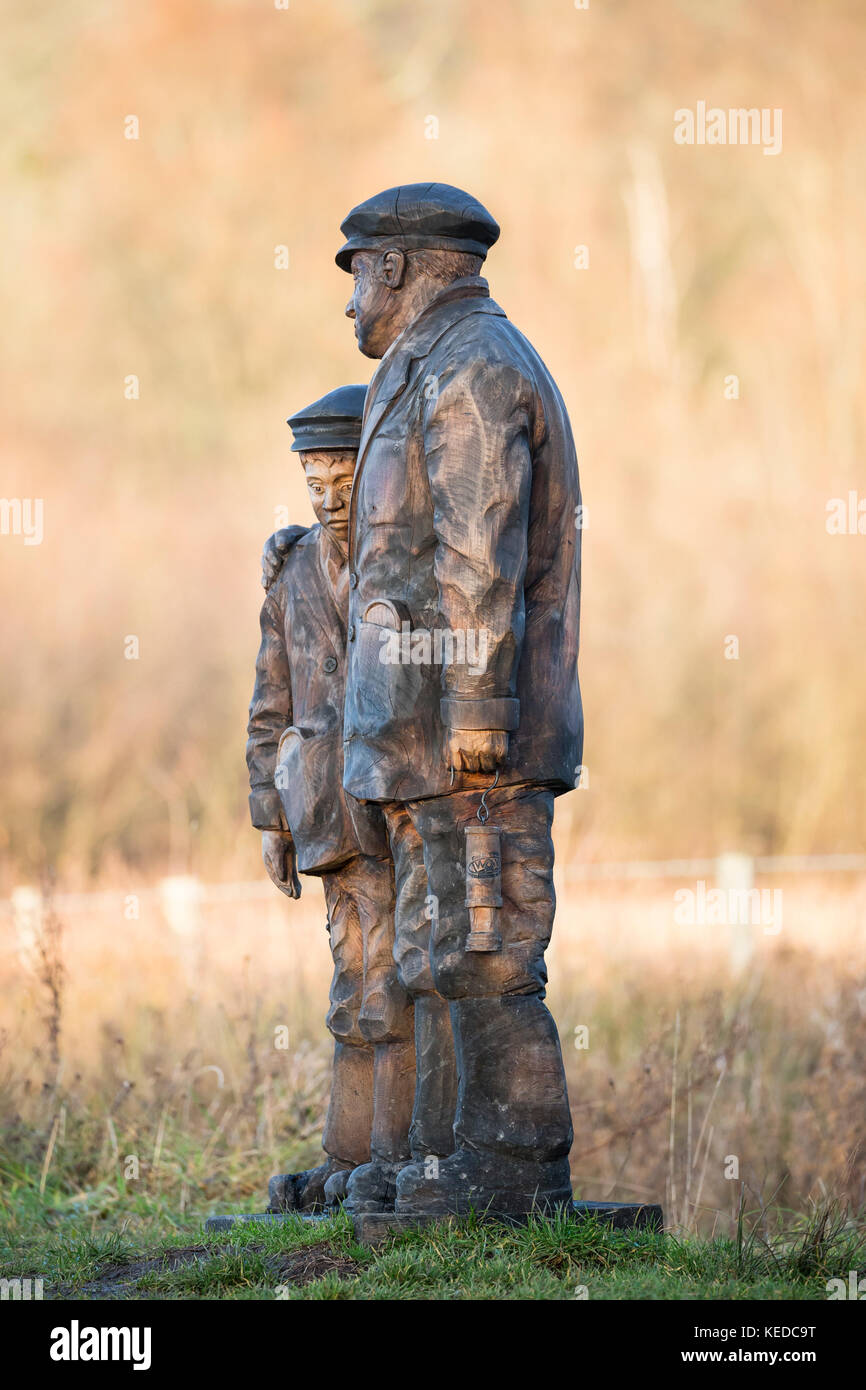 lifesize wooden sculpture of lifelike miner and boy Stock Photo