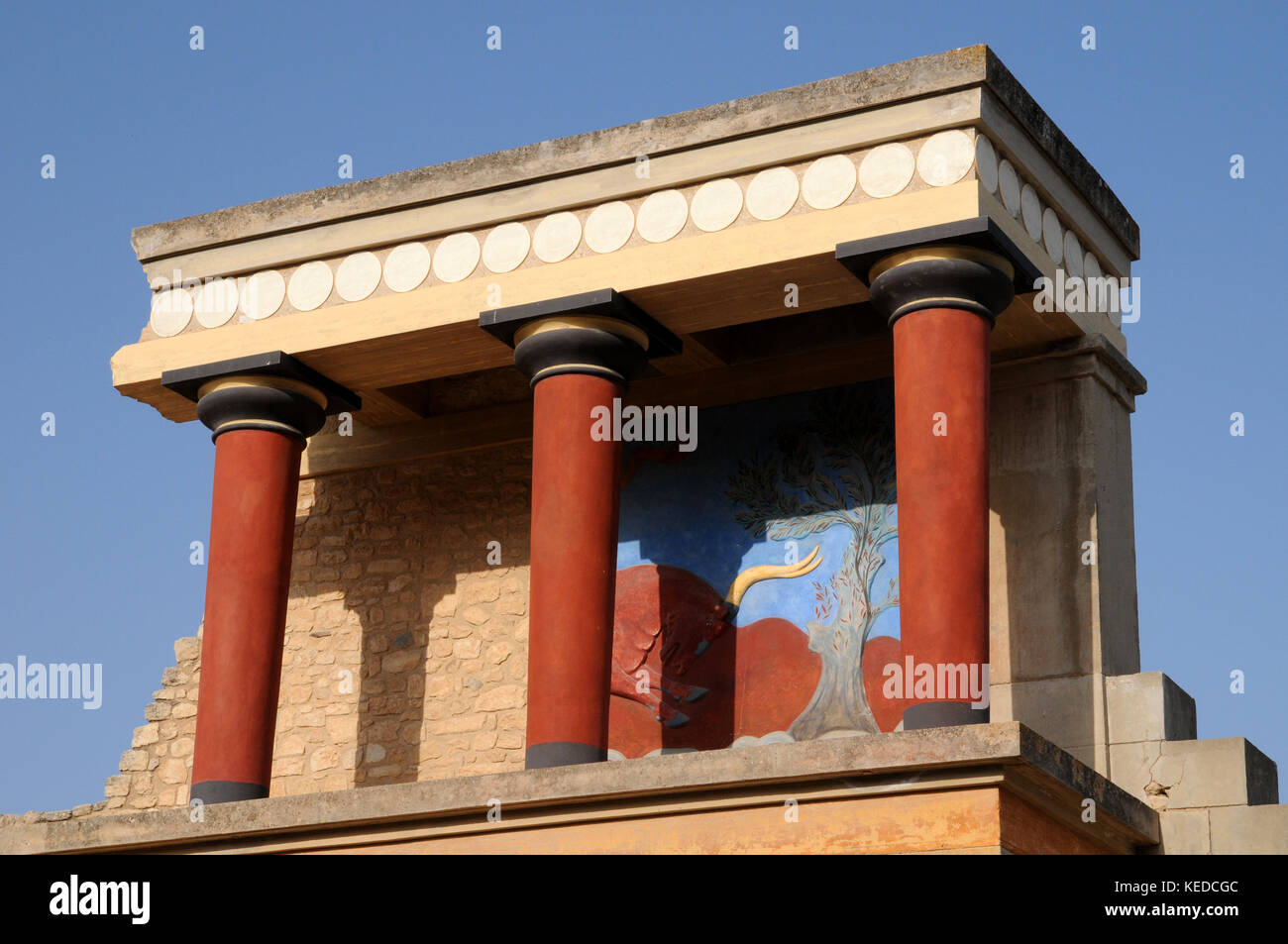 Restored columns and fresco at the Minoan Palace of Knossos in Crete. This is known as The Bastion of the Bull, after the fresco behind the columns. Stock Photo