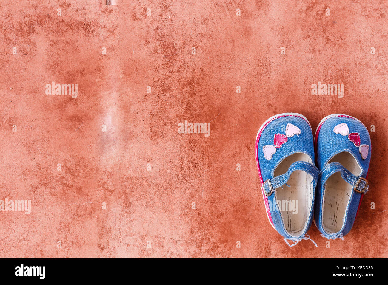 Denim Mary Jane style baby shoes with three hearts across the toes. Minimalist appearance. Stock Photo