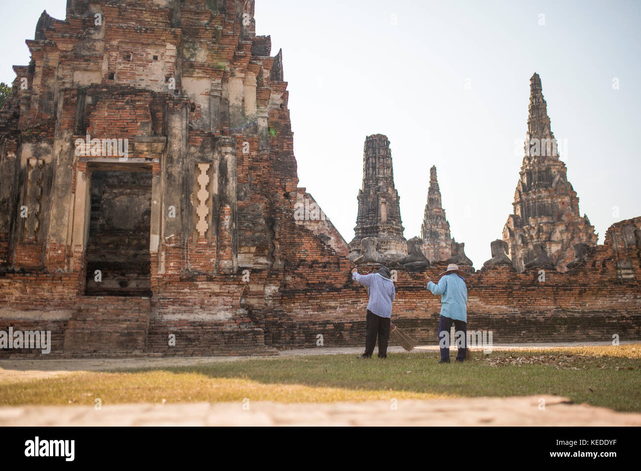 Two workers are picking up leaves in the Wat Chaiwatthanaram complex in Ayutthaya city, Thailand. Stock Photo