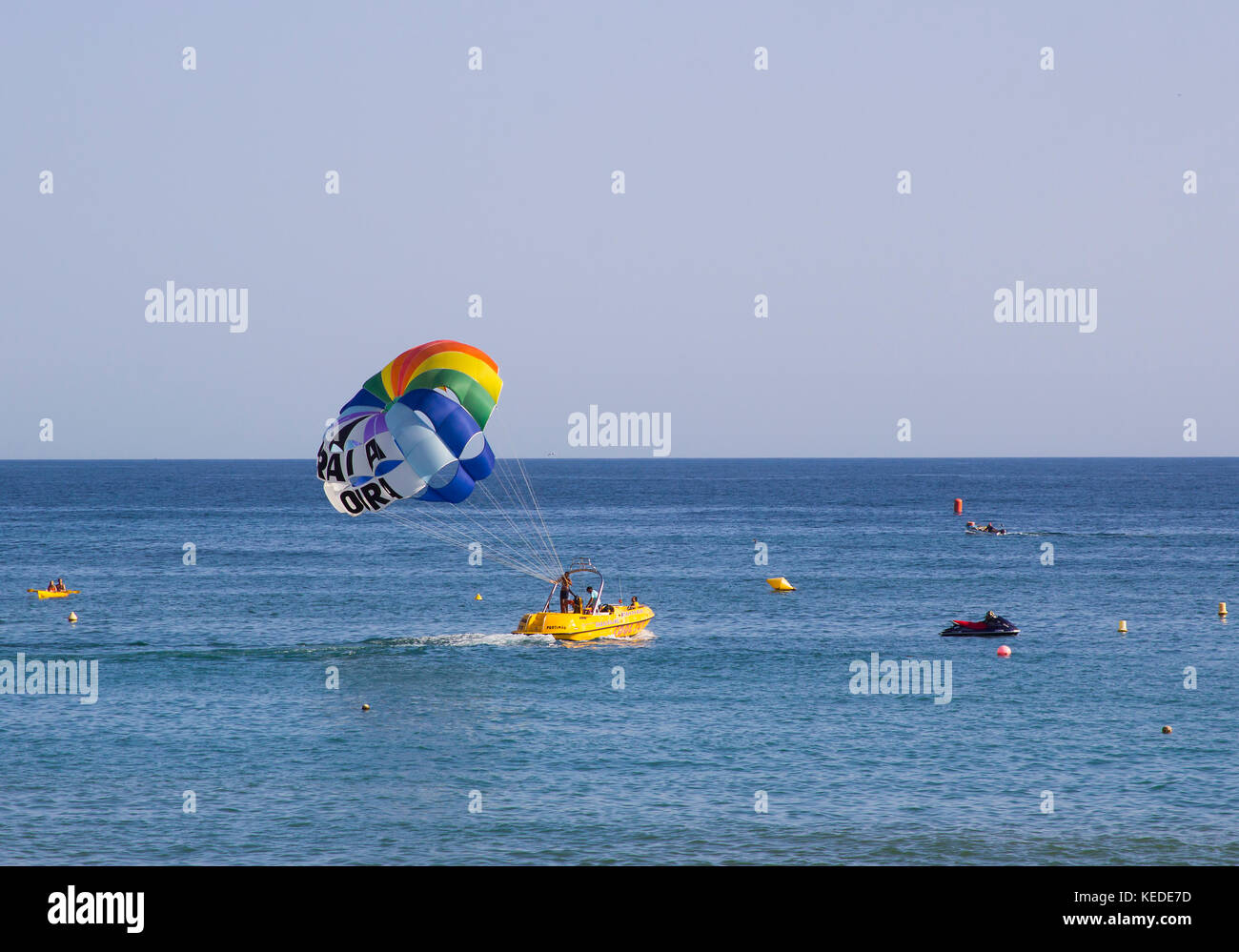 Local instructors prepare their customer for a paragliding experience from the back of their boat at the Praia Da Oura beach in Albuferia in the Portu Stock Photo