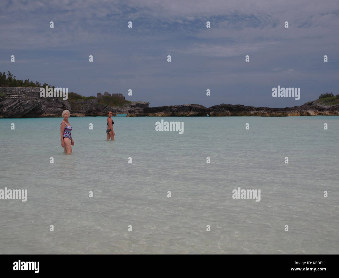 Knee deep in the soothing warm Bermuda water near Castle Harbor, Bermuda two bathers enjoy the solitude of their own private retreat. Stock Photo