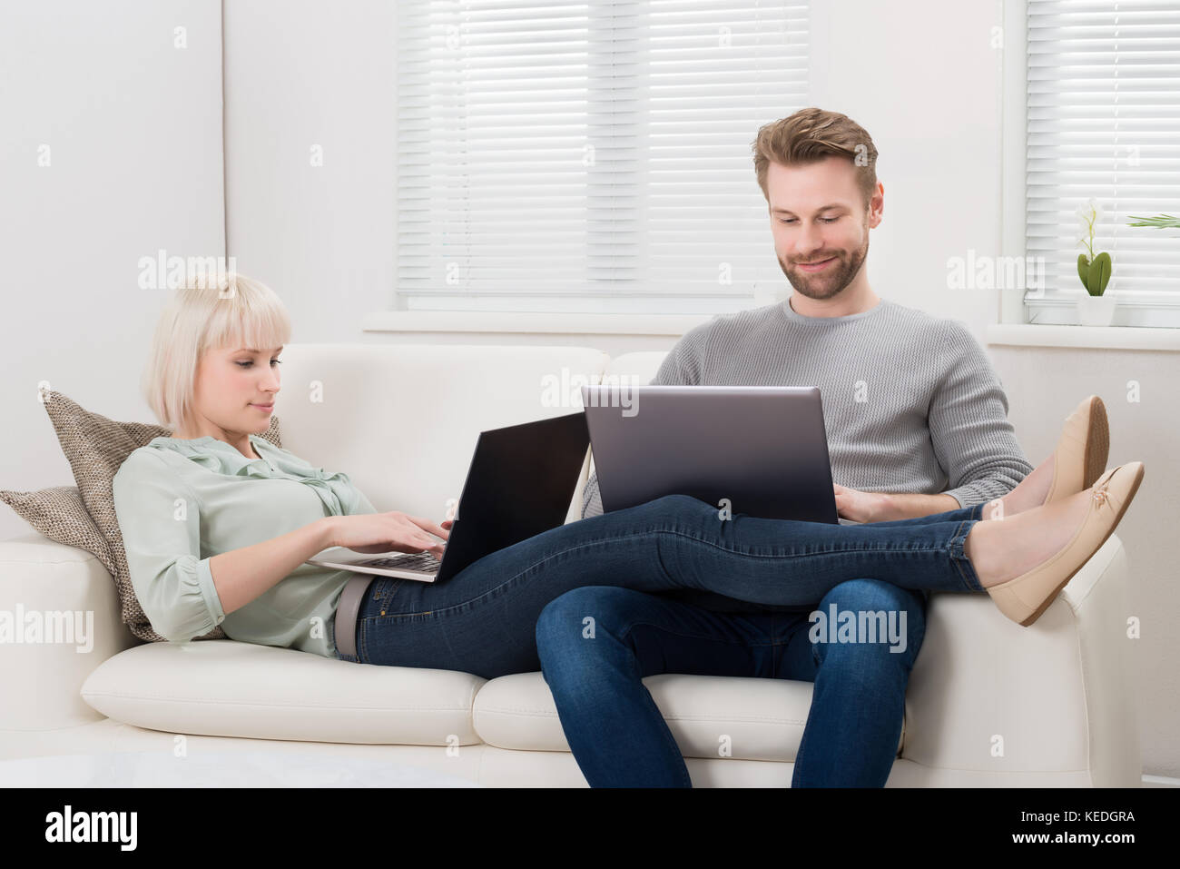 Young Couple Relaxing On Sofa Using Laptop At Home Stock Photo - Alamy