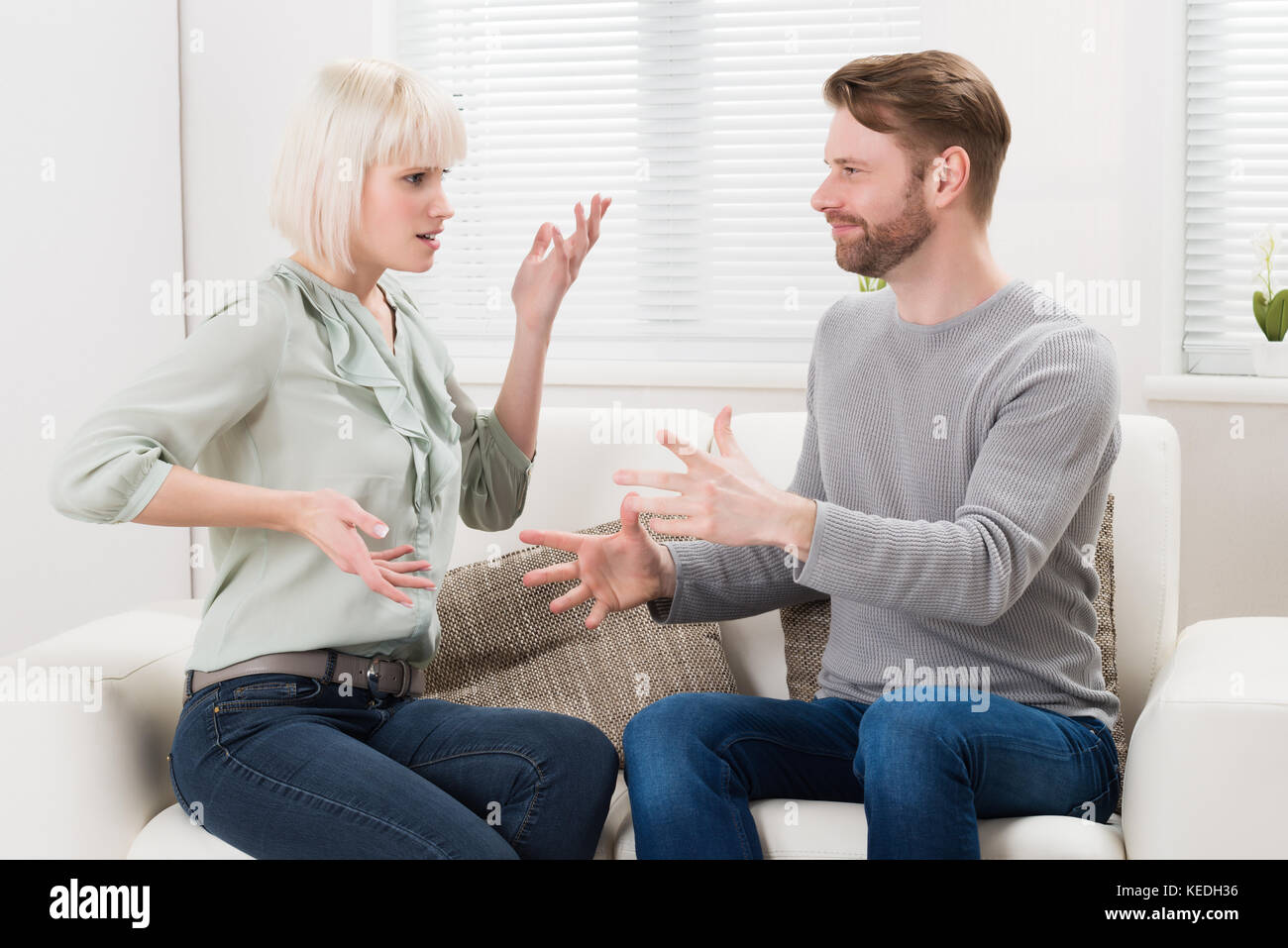 Couple Sitting On Couch Quarreling With Each Other Stock Photo