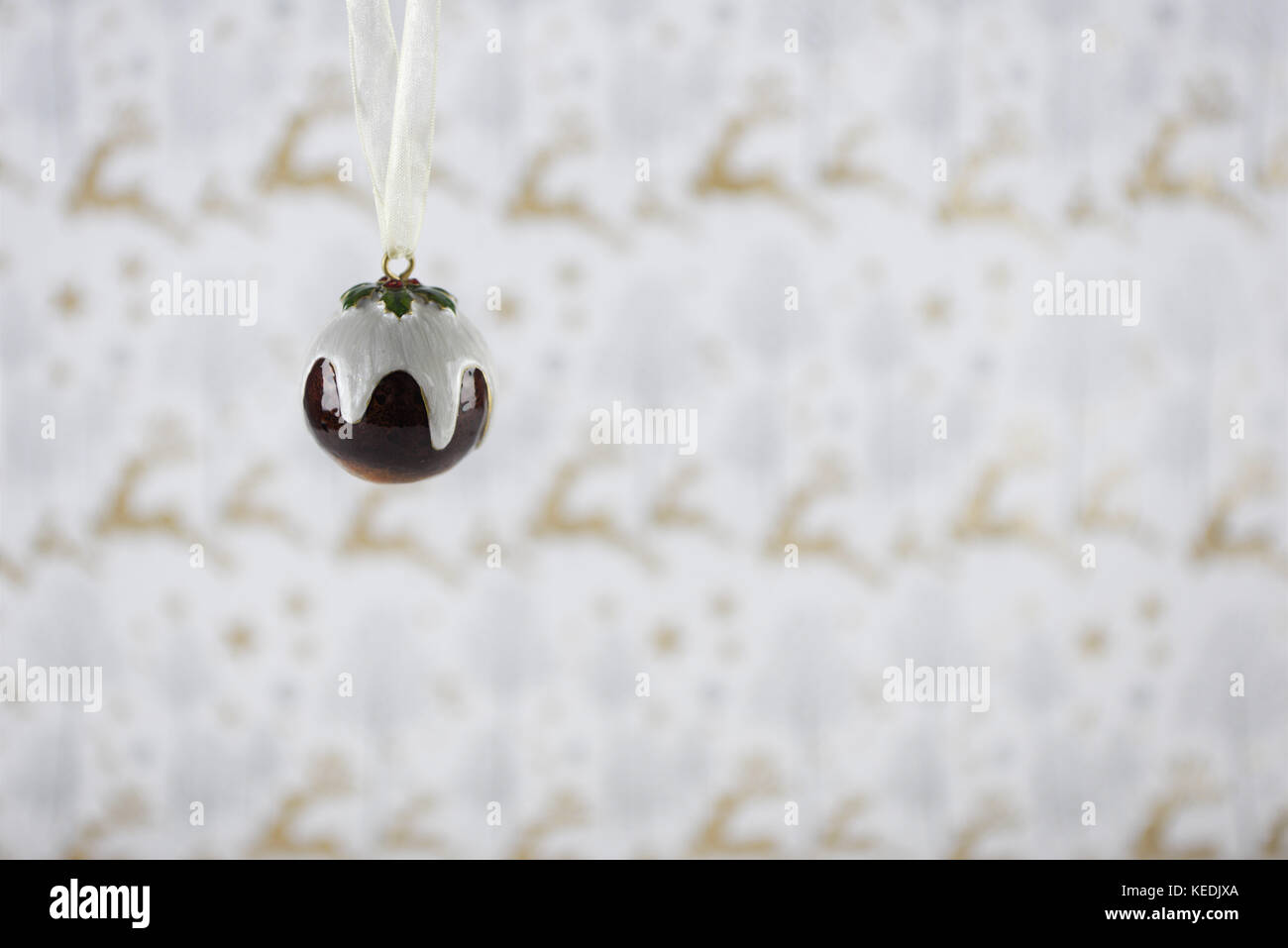 Christmas photography image of Christmas decoration hanging up of xmas pudding cream holly with gold glitter reindeer xmas wrapping paper background Stock Photo