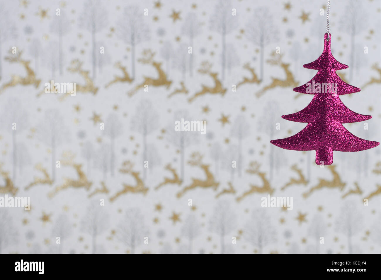 Christmas photography image of Christmas decoration hanging up of pink glitter xmas tree with gold glitter reindeer xmas wrapping paper background Stock Photo