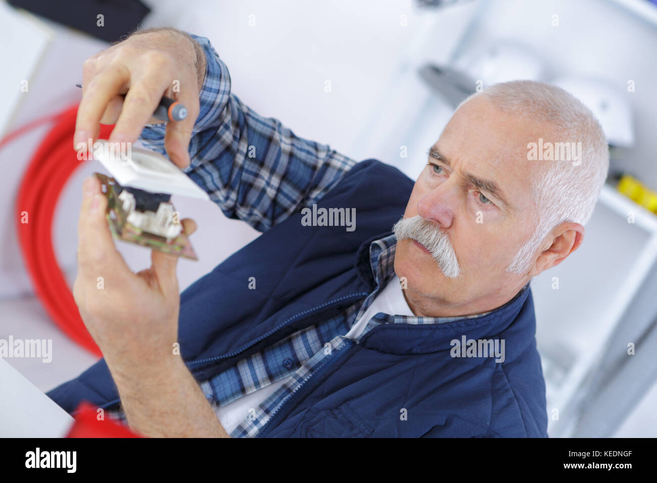 Photo inspiration: Visiting Electronics Repair For Seniors At Home Reference: Senior Tech Or Engineer Repairs Electronic Equipment Stock Photo