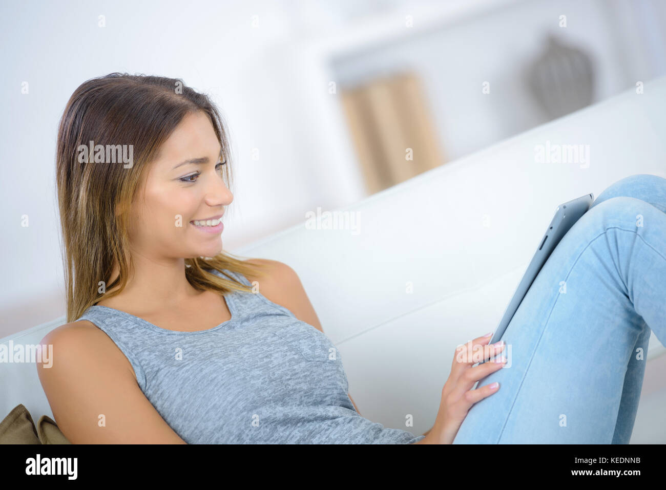 young smiling woman sitting on sofa with tablet Stock Photo - Alamy