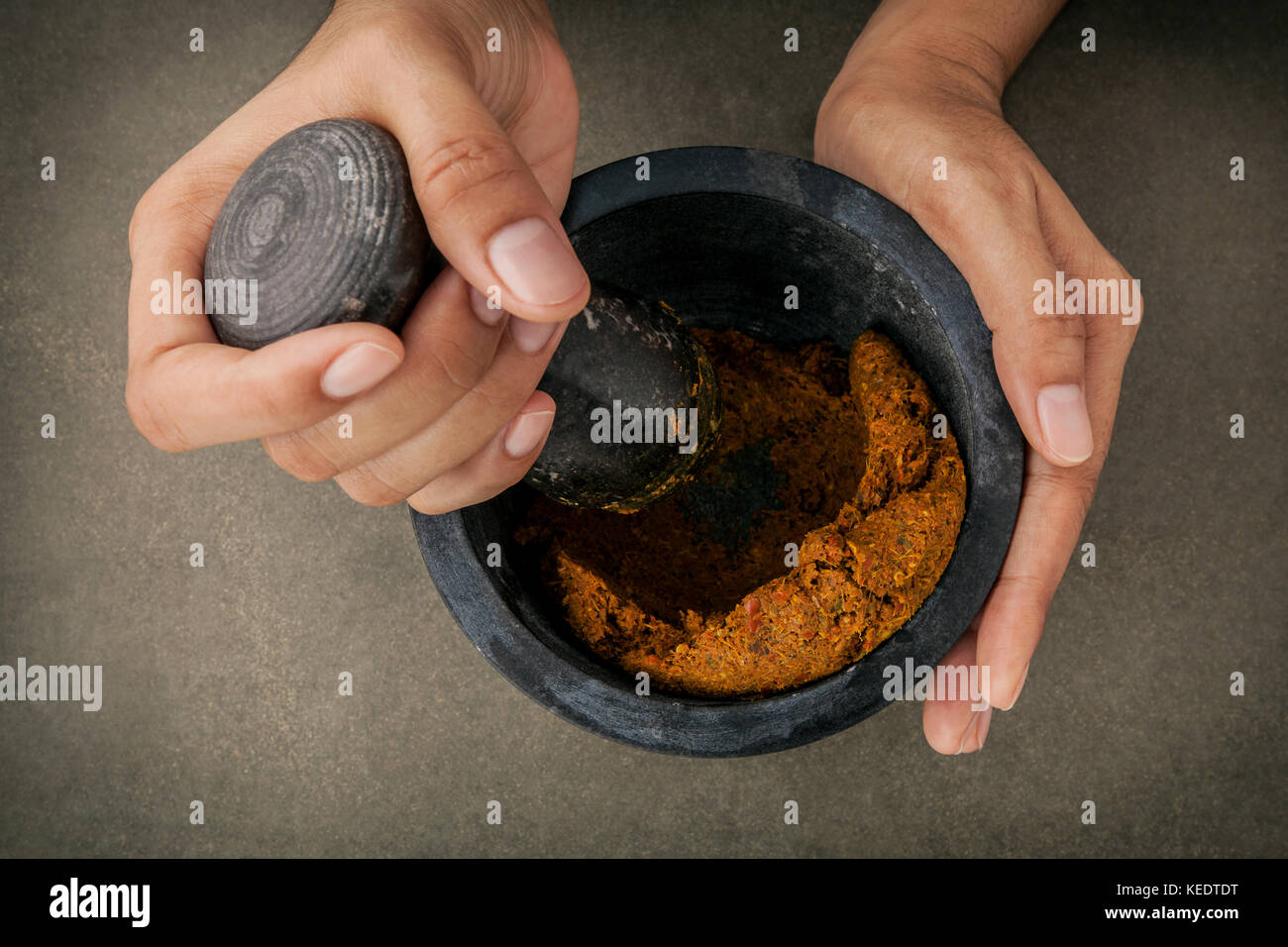 The Women hold pestle with mortar and and spice red curry paste