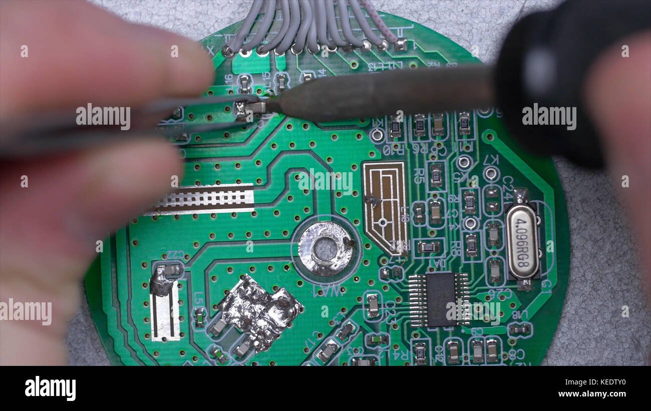 Hand holding soldering gun and working with lead repair board