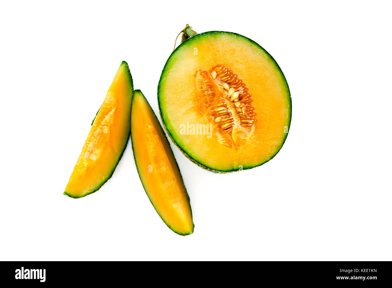 Ripe yellow melon with seeds cut in half with slices nearby. Isolate on white background. Stock Photo