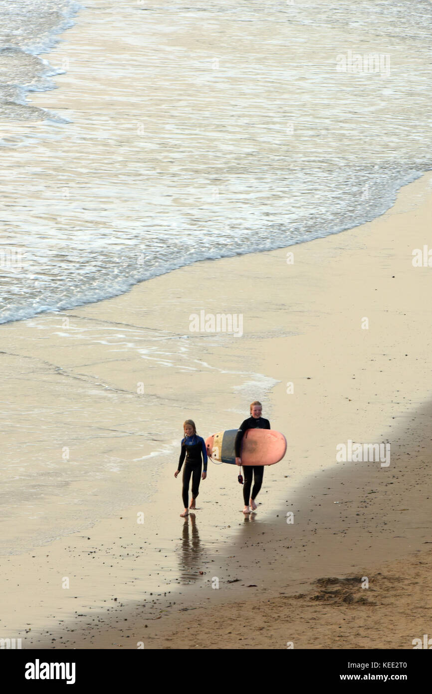 two people walking on a sandy beach at sunset carrying a surfboard with the  waves and surf at their wet feet paddling in the sea at the seaside Stock  Photo - Alamy, image size:866x1390