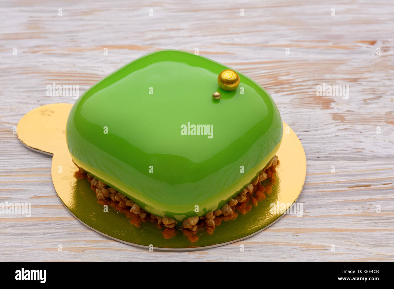 Trendy green mousse cake with mirror glaze decorated. wooden background. Close-up view Stock Photo