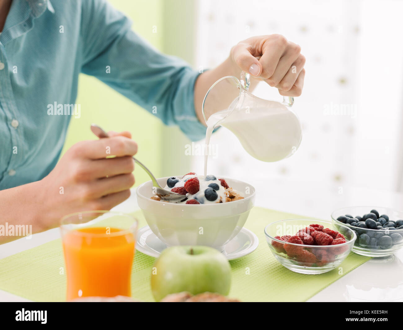 Woman having an healthy delicious breakfast at home, she is pouring ...