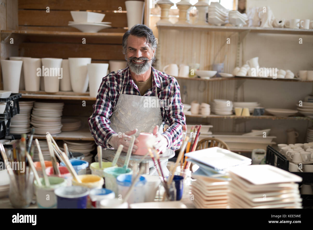 Portrait of male potter holding bowl in pottery workshop Stock Photo ...