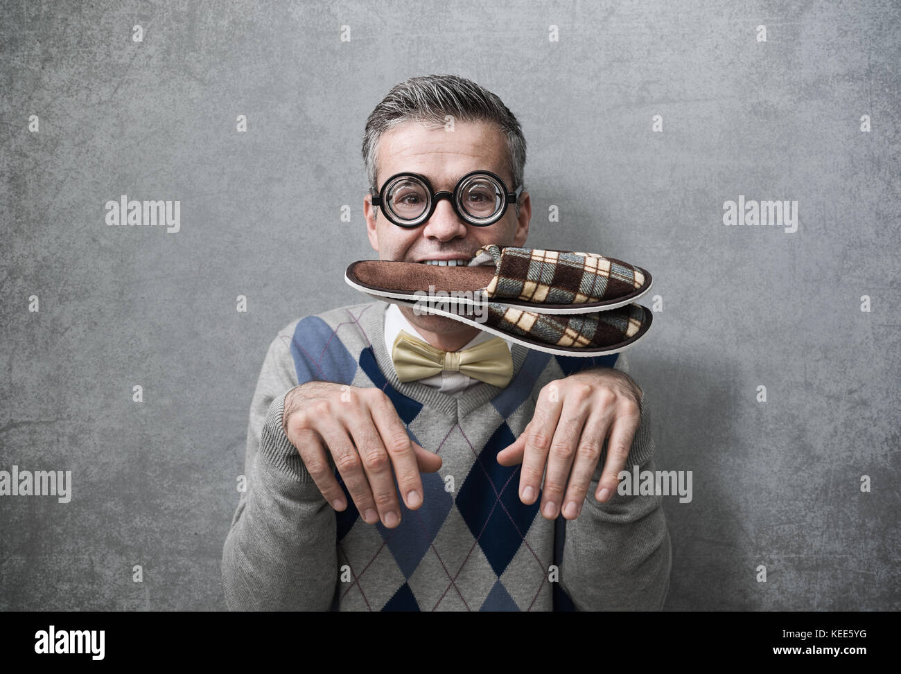 Submissive man acting like a dog and carrying slippers in his mouth, obedience and humiliation concept Stock Photo