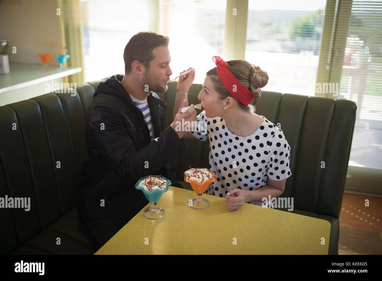 Couple feeding ice cream to each other in restaurant Stock Photo Alamy