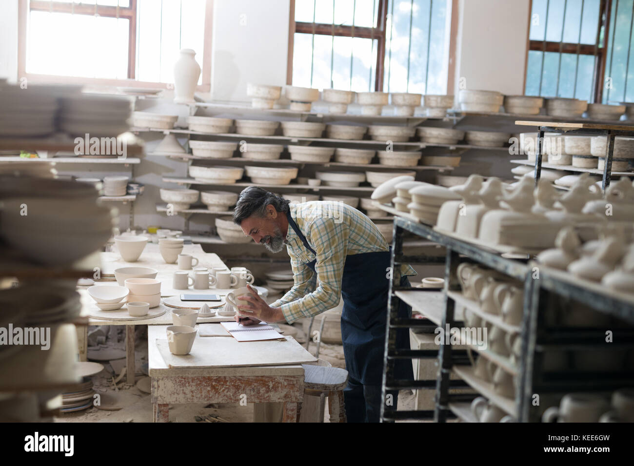 Male potter checking bowl in pottery workshop Stock Photo - Alamy
