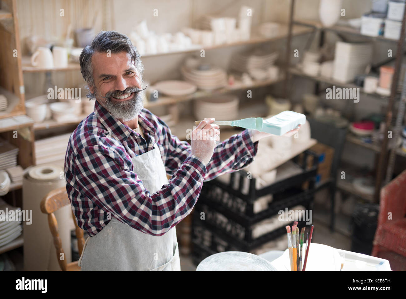 Portrait of smiling male potter painting slab in pottery shop Stock ...