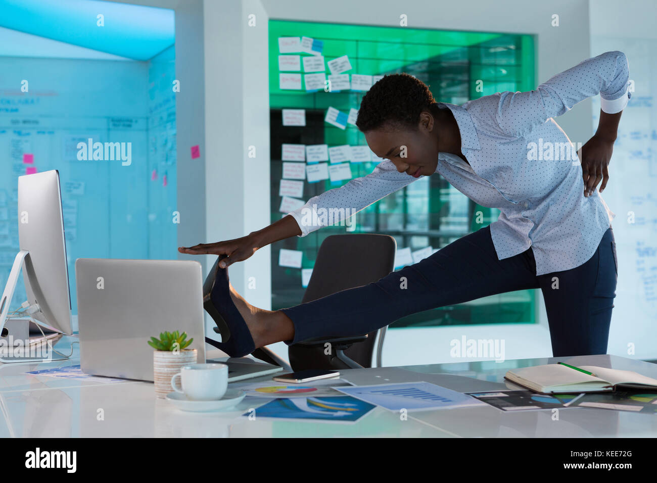 Female Executive Performing Exercise At Desk In Futuristic Office Stock Photo Alamy