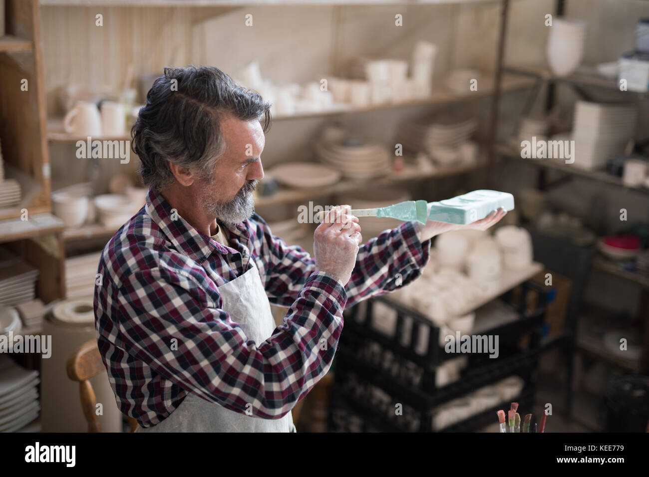 Male potter painting slab in pottery shop Stock Photo - Alamy