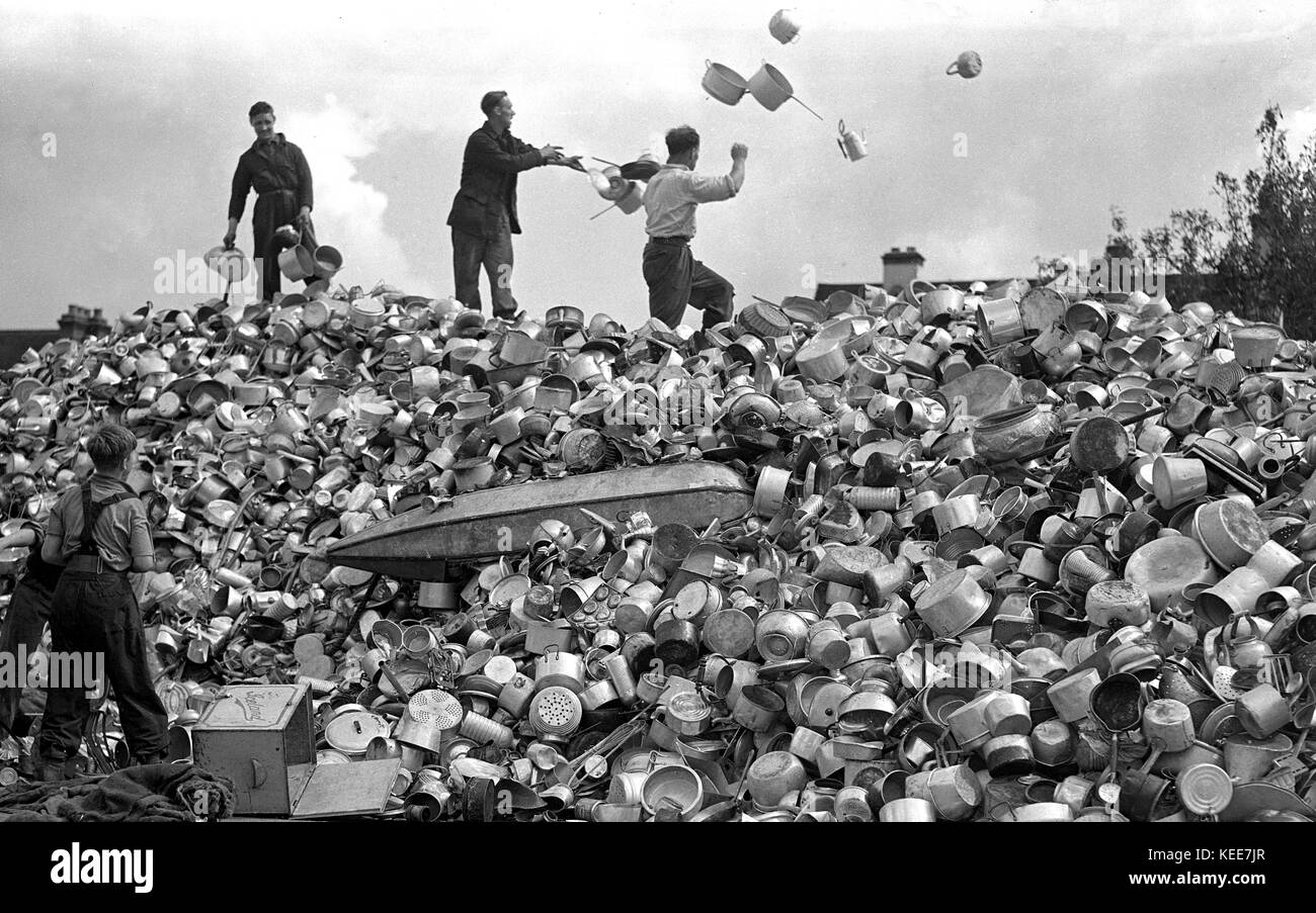Men and boys sift through a mountain of pots and pans donated by the British public towards the war effort. During World War Two in 1940, Lord Beaverbrook launched an appeal for aluminium to help build Spitfire fighter aeroplanes and the public responded emphatically with kitchenware, containers and anything that could be used donated all over the country.c1940.  Photograph by Tony Henshaw *** Local Caption *** From the wholly-owned original glass negative. From the wholly-owned original negative. Stock Photo