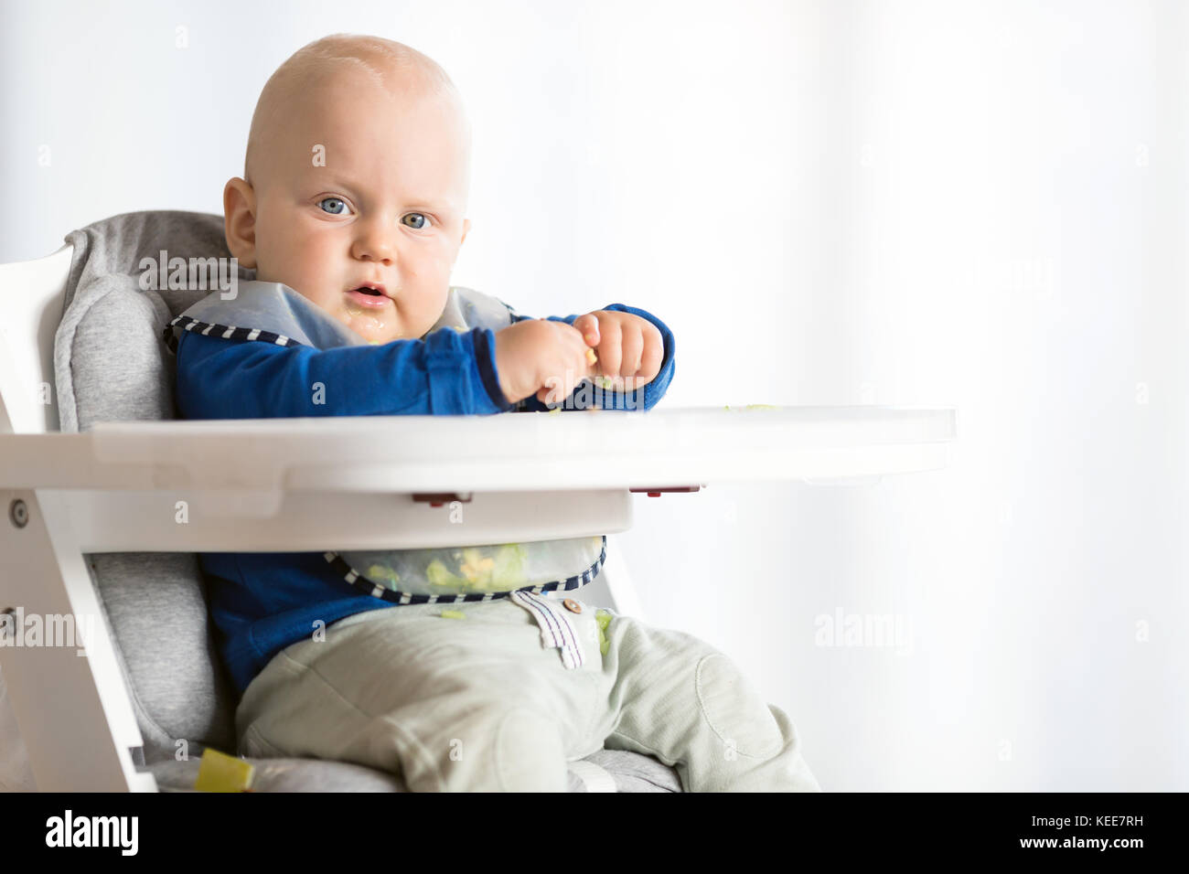 Baby boy eating bread and cucumber with BLW method, baby led weaning
