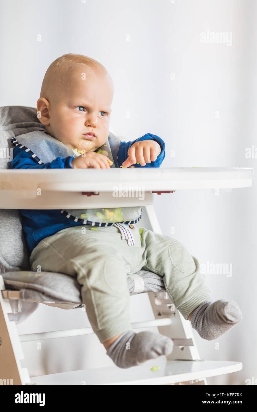 Baby boy eating bread and cucumber with BLW method, baby led weaning
