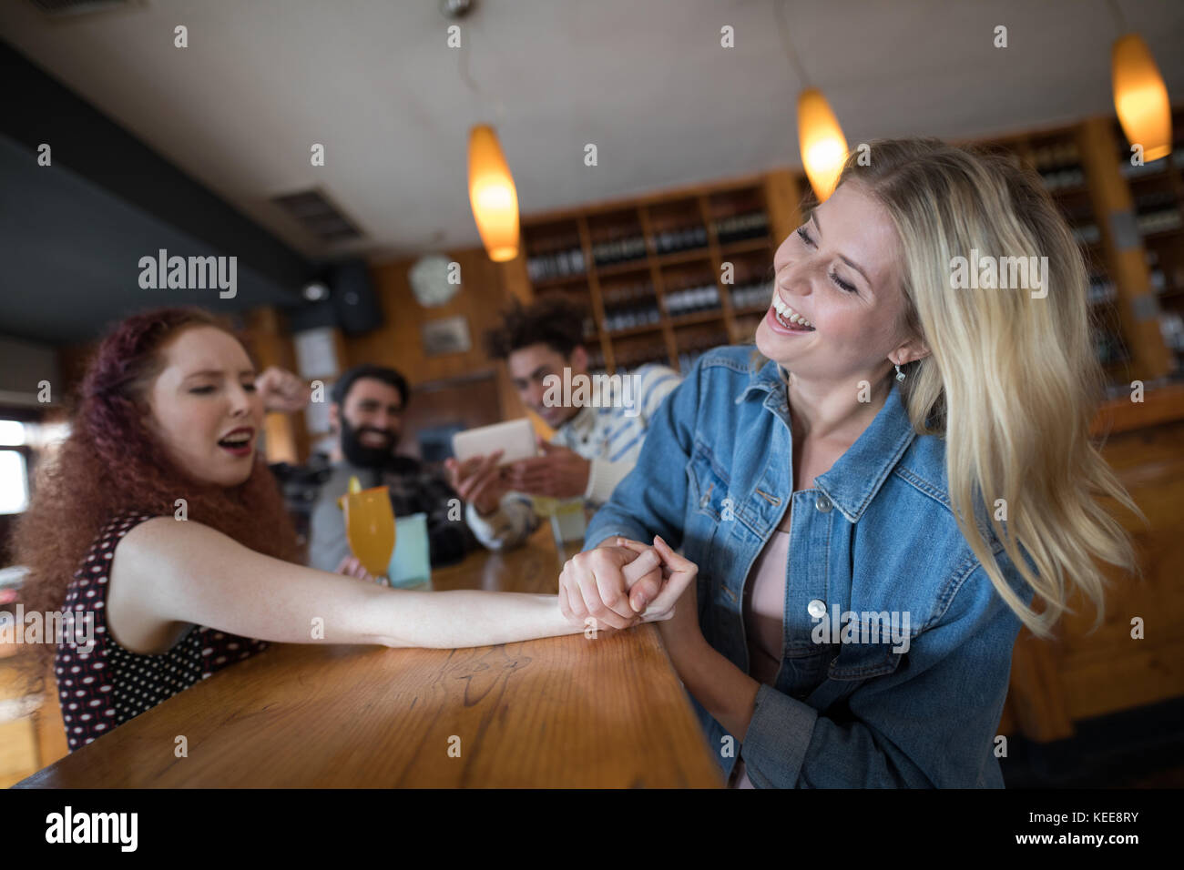 Women arm wrestling and men capturing a shoot in bar Stock Photo Alamy