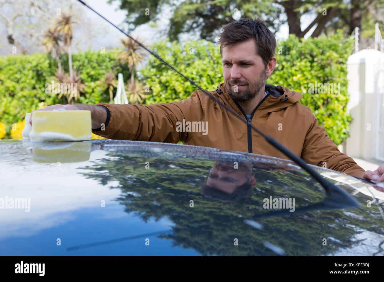 Male auto service staff washing a car roof with sponge Stock Photo