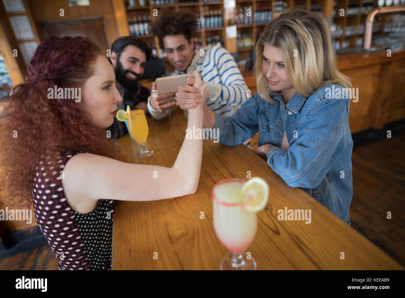 Women arm wrestling and men capturing a shoot in bar Stock Photo Alamy