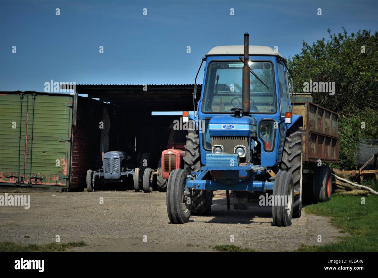 Small blue Ford tractor being used on English farm at harvest time Stock Photo