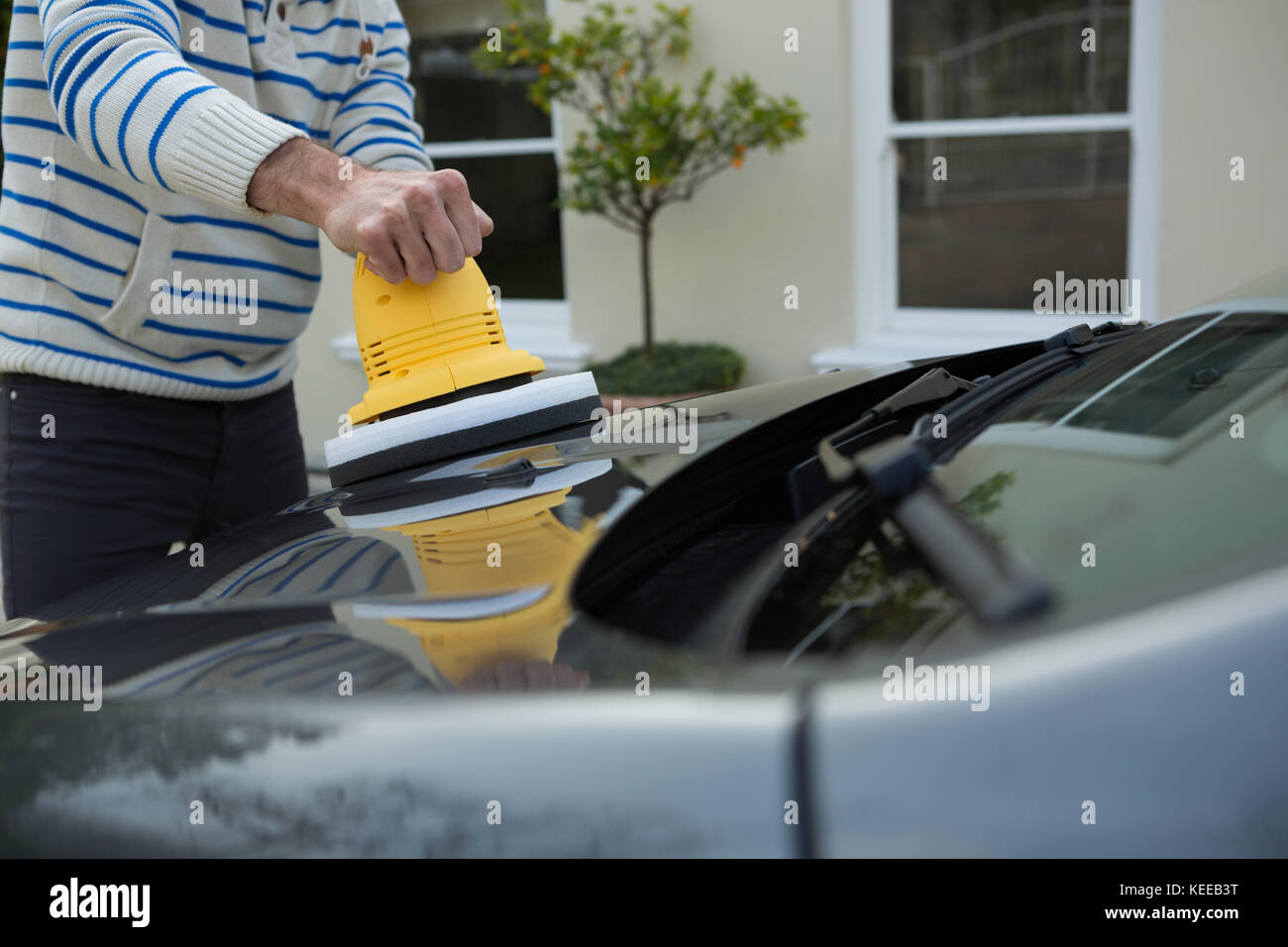 Male auto service staff cleaning a car with rotating wash brush