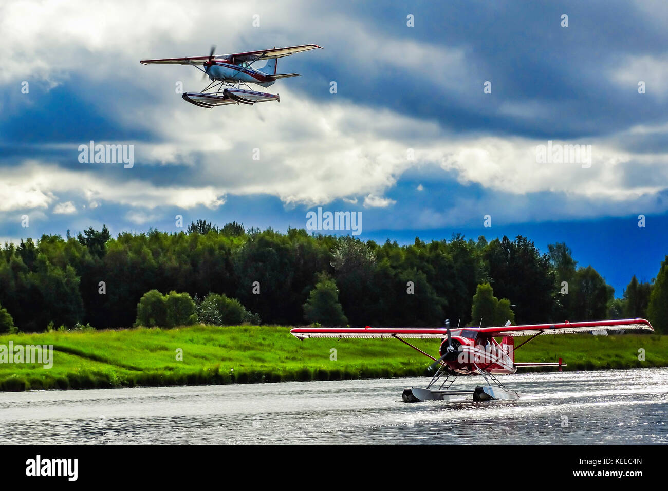 Two float planes, one flying, one taking off from the water, at Anchorage in Alaska Stock Photo