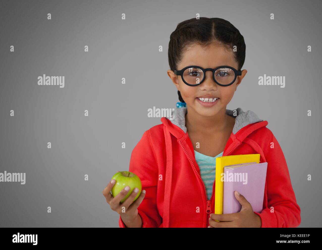 Digital composite of Girl against grey background with apple and books ...