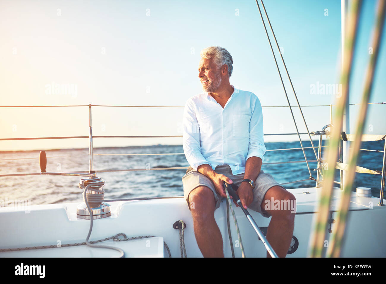 Smiling mature man sitting on the deck of his boat enjoying a sunny day ...