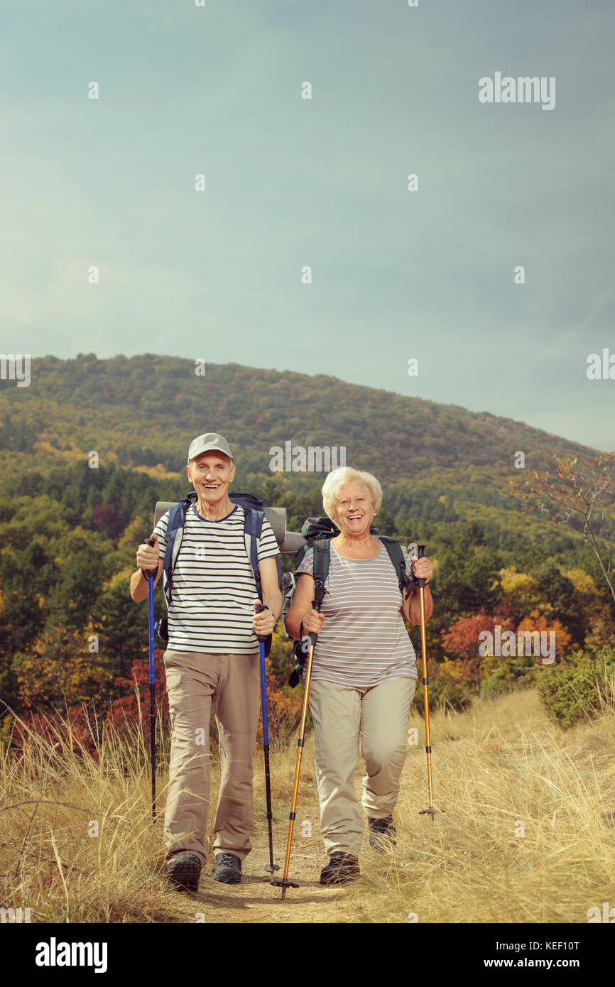 Full length portrait of two elderly hikers walking towards the camera outside Stock Photo