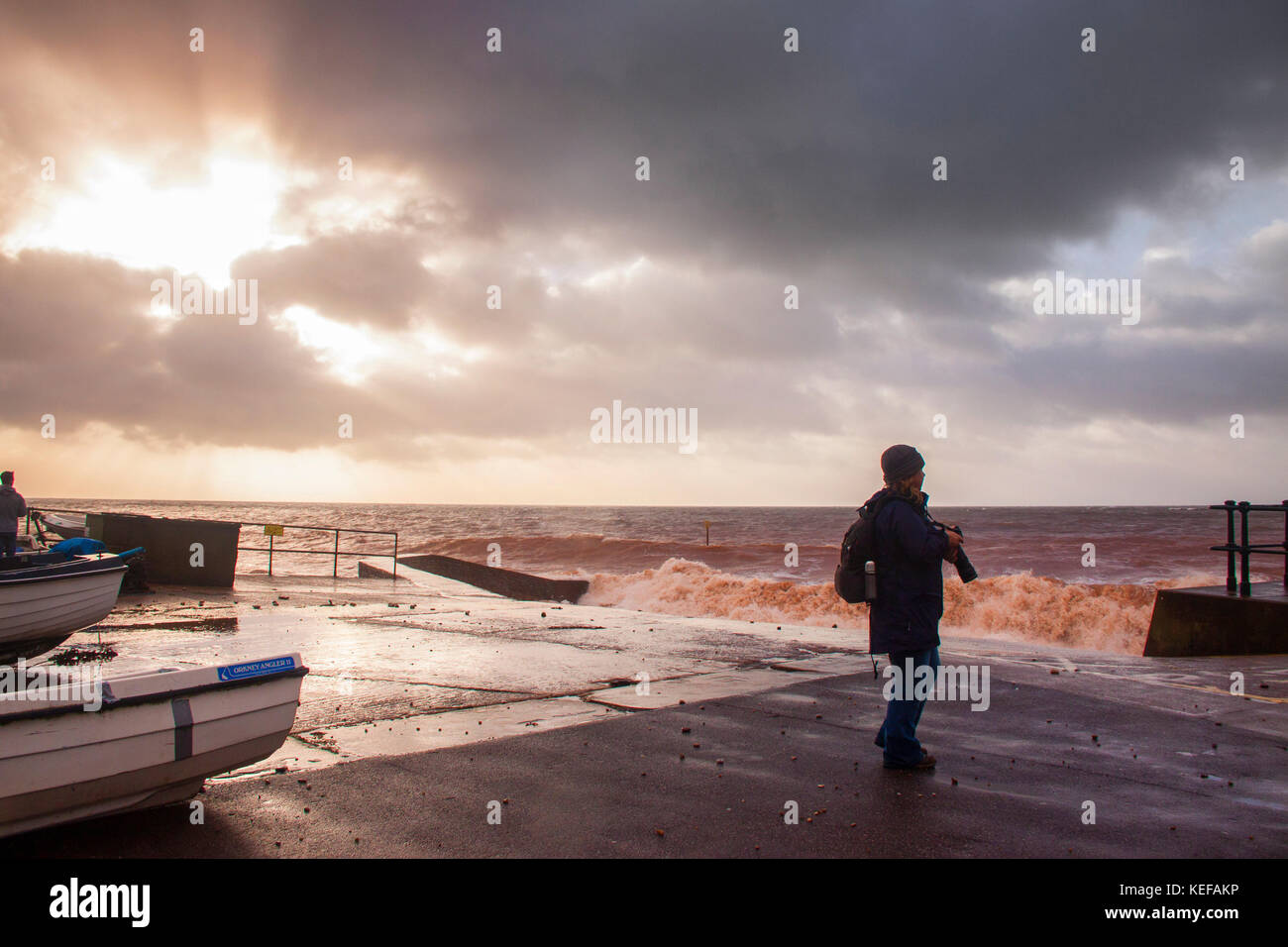Sidmouth, UK. 21st Oct 2017. UK Weather. People out just after dawn to watch as Storm Brian hits Sidmouth, in Devon. In stormy weather, the red sandstone of the area turns the sea red at Sidmouth. Credit: Photo Central/Alamy Live News Stock Photo