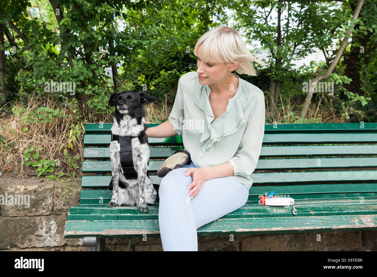 Young Woman Sitting With Her Dog On The Bench Stock Photo - Alamy