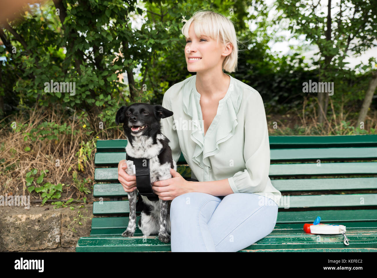 Young Happy Woman Sitting With Her Dog On The Bench Stock Photo - Alamy